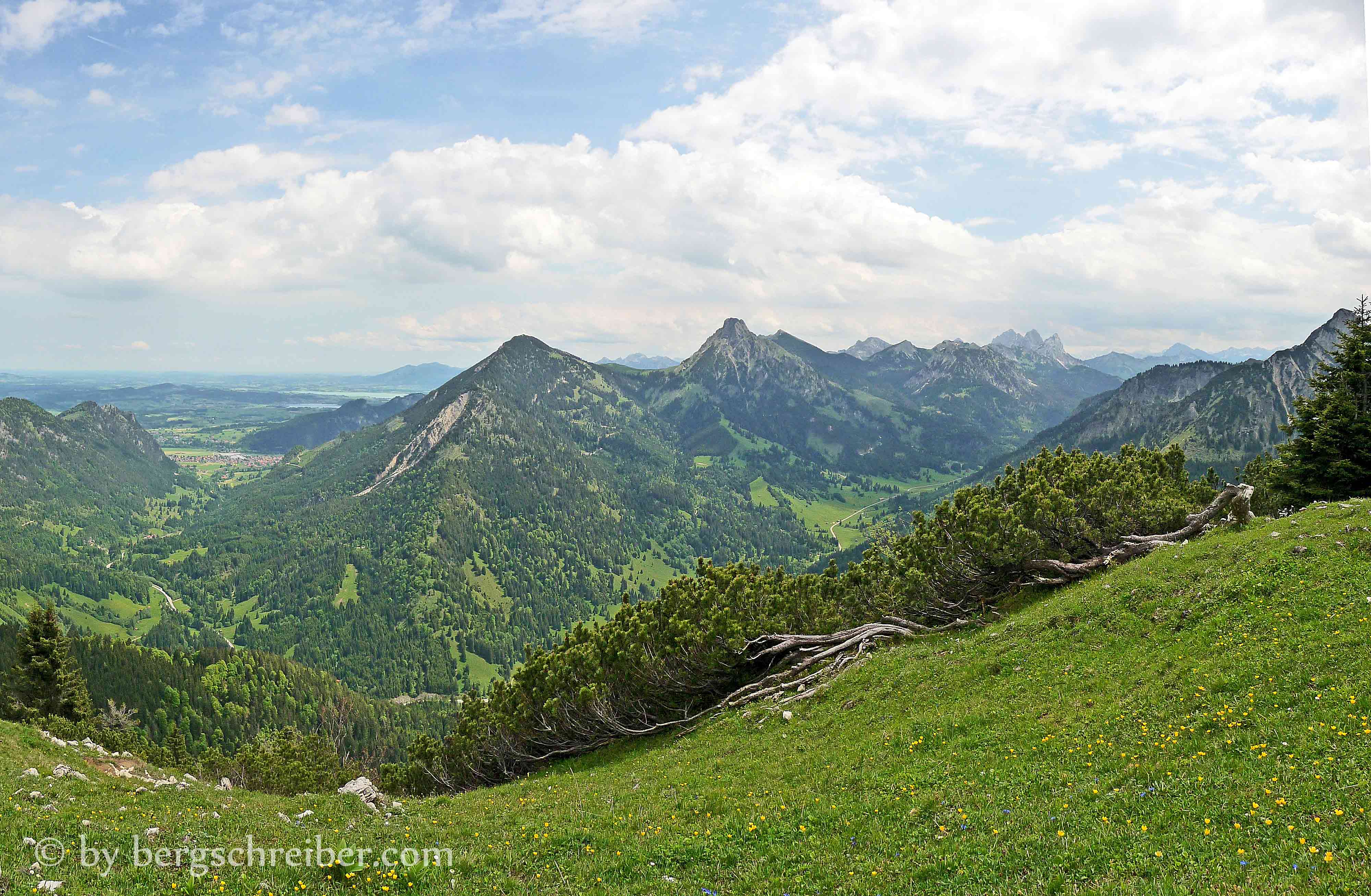 Im Tal die Ortschaft Pfronten, im Voralpenland Hopfensee und Forggensee. Breitenberg, Aggenstein und die Tannheimer Berge.